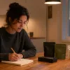 Adult shopper makes notes while comparing three discreet delivery packages at a kitchen table.